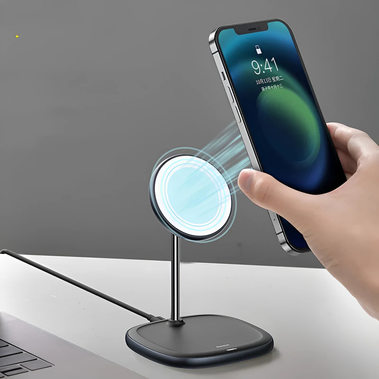 Black magnetic wireless charging stand holding an iPhone 12 upright on a desk.