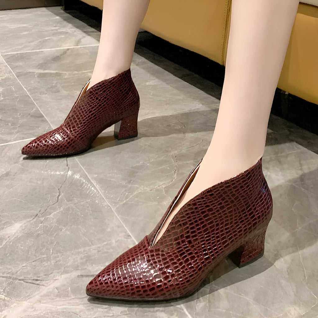 Women's black V-cut pointed toe Martin boots with embossed detail and a chunky heel.