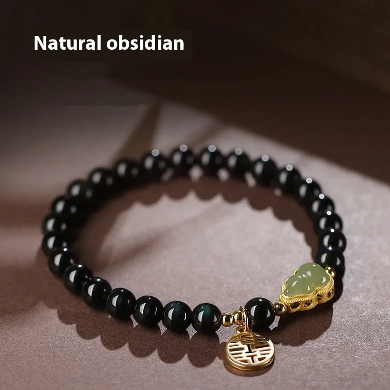 Black obsidian bead bracelet with a carved Hetian jade gourd charm in geometric pattern.