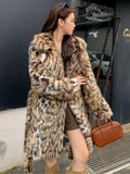 A person wearing a grey faux fur coat with a large fur collar and front pockets, in a street-fashion style.