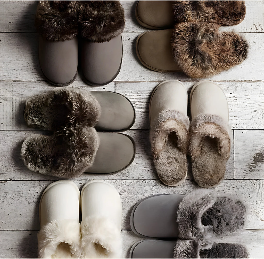Beige couple wool slippers with suede upper and artificial wool trim on a wooden floor