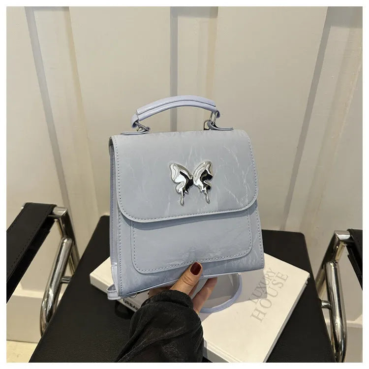 Preppy style white PU women's backpack with a black detachable bow decoration and visible stitching.