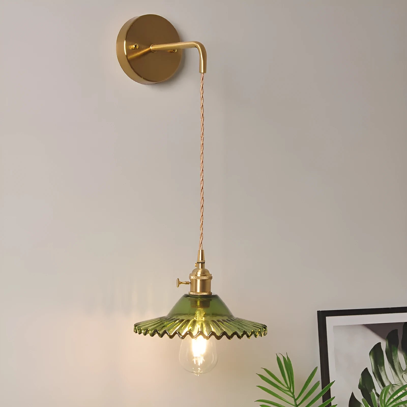 Brass wall lamp with an adjustable smoked grey glass lotus shade mounted beside a bed.