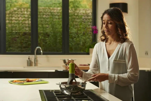 Green and grey automatic Stirr utensil for hands-free mixing in a cooking pot.