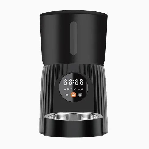 Black automatic pet feeder with digital display and food bowl on a kitchen counter.