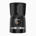 Black automatic pet feeder with digital display and food bowl on a kitchen counter.