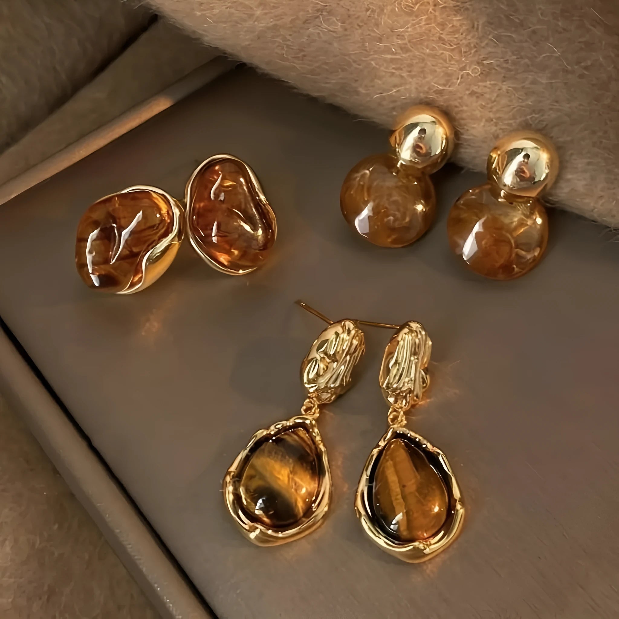 Three pairs of geometric earrings with tassel detailing in different styles: round, irregular, and water drop shapes.