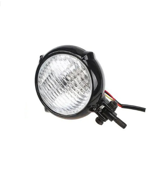 Black circular aluminium Harley-style motorcycle headlight with a coloured glass lens.
