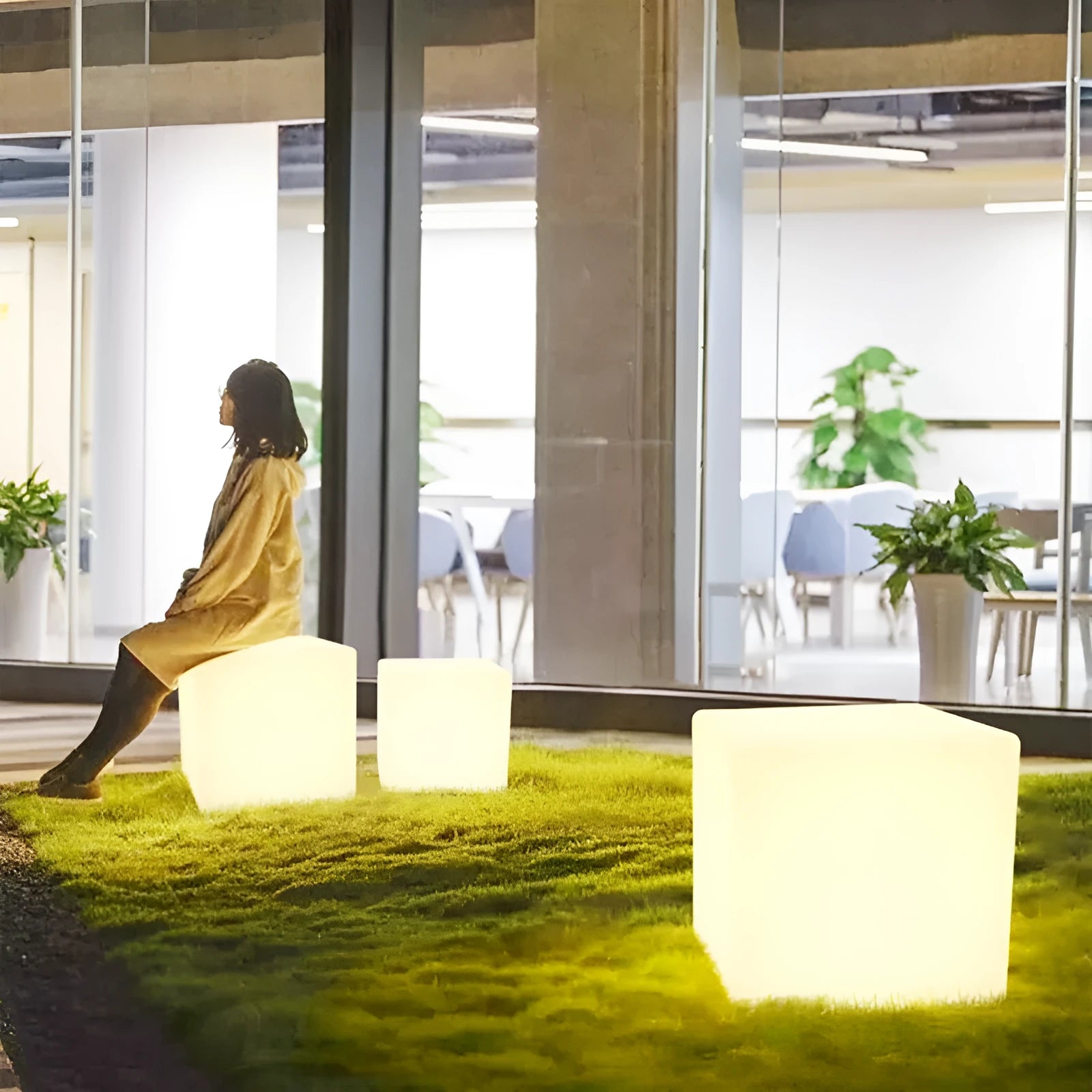 A modern square white LED cube light functioning as a waterproof stool for outdoor gardens.