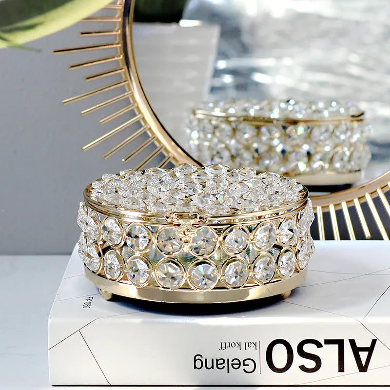 Crystal clear glass jewelry box with French gold metal frame on a table.