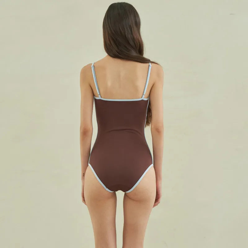 Brown women's one-piece triangle swimsuit on a hanger, showing nylon fabric texture.