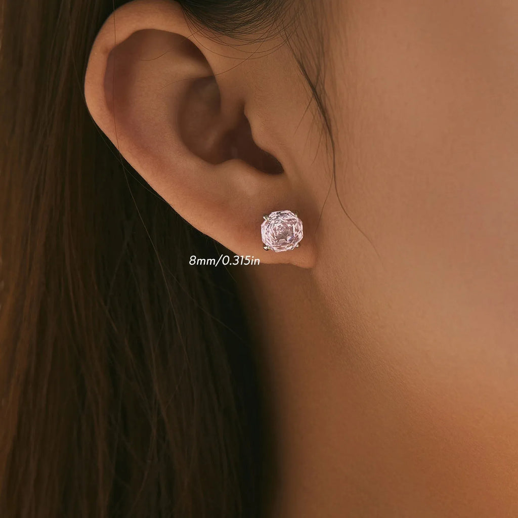 Close-up of S925 sterling silver rose stud earrings for women on a pink background.