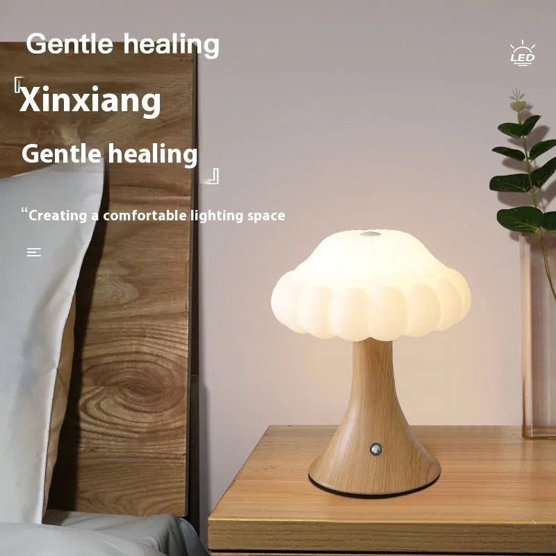 Wood grain coloured mushroom-shaped touch lamp with USB charging port on a bedside table.