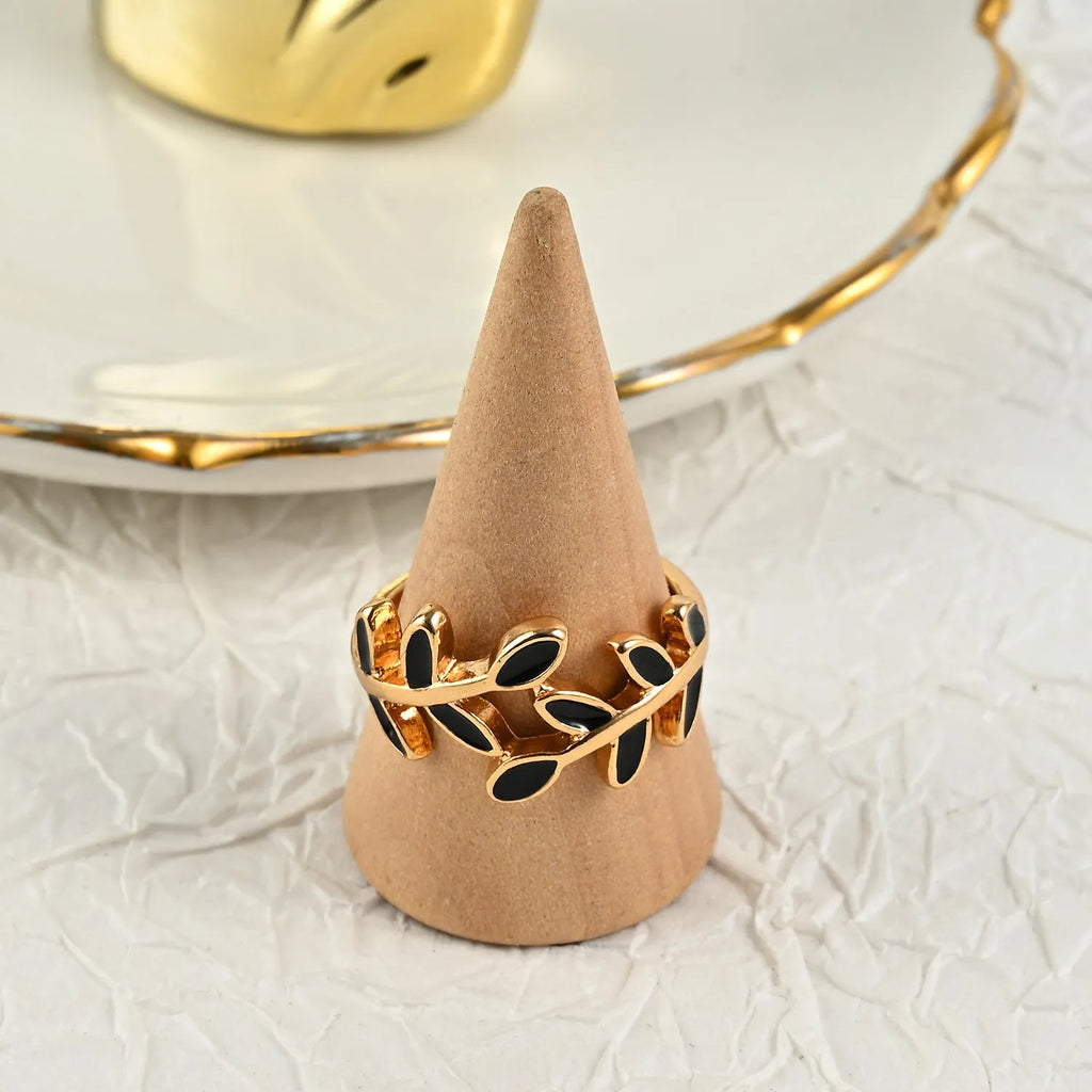 Gold electroplated acrylic ring with a geometric leaf and flower design on a model's index finger.