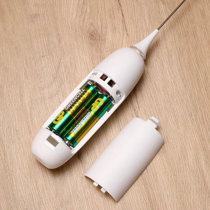 Black and white hand-held electric milk frother and blender on a kitchen counter.