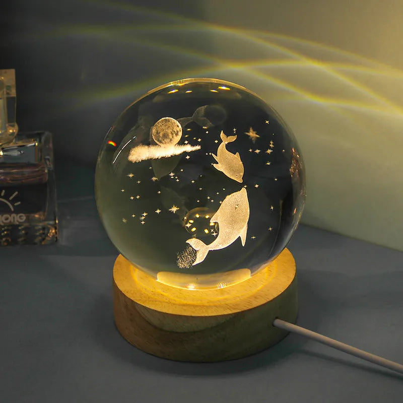 Transparent crystal ball night lamp with 3D carved jellyfish design, lit with soft blue glow on a round base.
