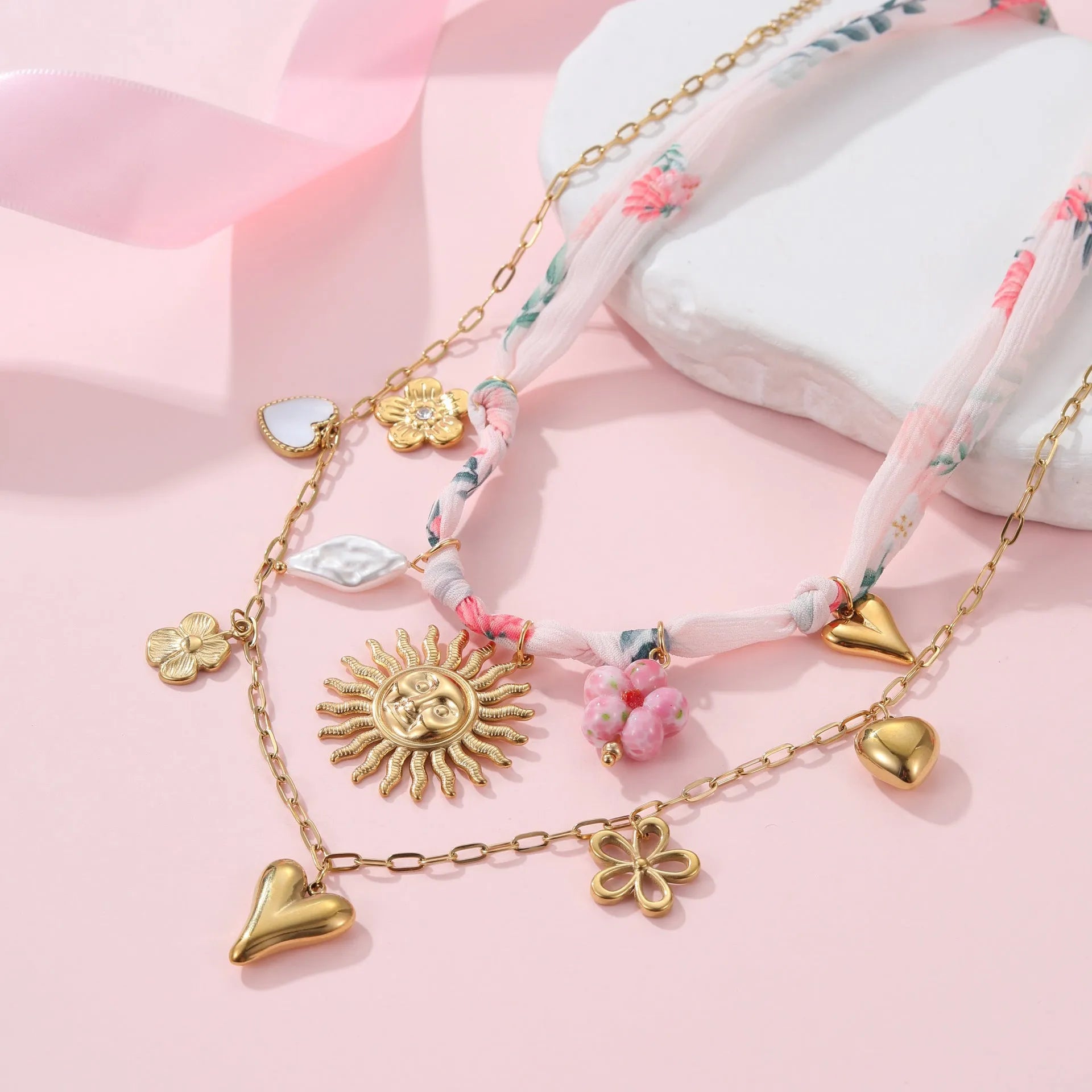 Stainless steel pendant necklace with 18K gold electroplating, showing heart and ribbon sun style options on an adjustable chain.