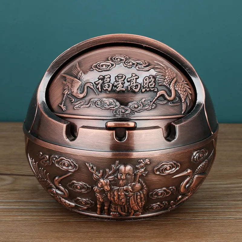 Alloy decorative ashtray in bronze with ornate peacock motif and cigarette extinguishing slot.