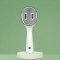 Dark green pet grooming comb with UVC sterilisation light, slicker brush, and needle comb on a grey background.
