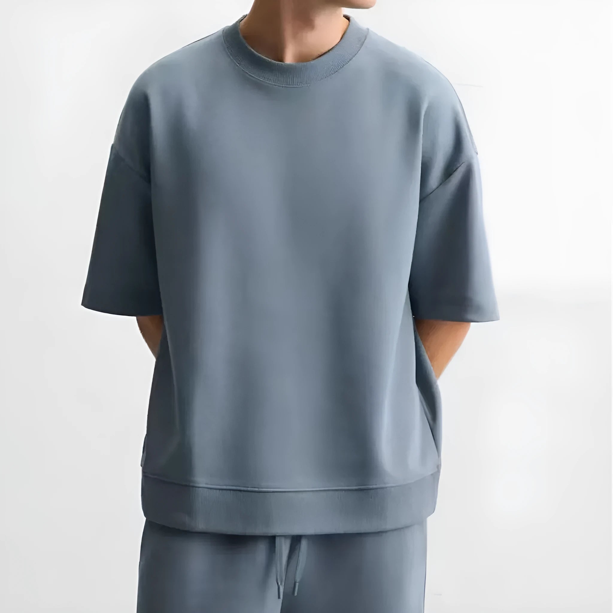 Man wearing a loose blue short sleeve top and matching shorts from a casual polyester co-ord set.