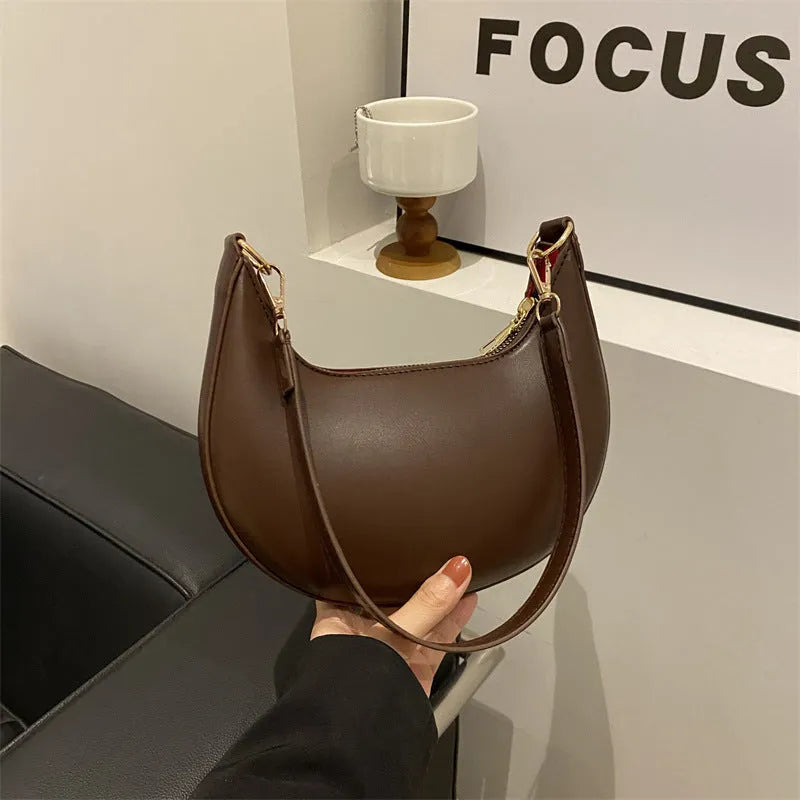 Round black women's one-shoulder underarm bag with sewing line details and a single strap.