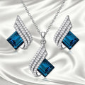 Silver-toned necklace and earrings set with glass pendant on cross chain