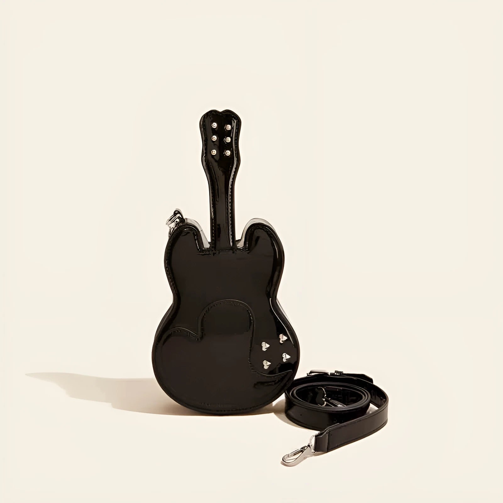 Guitar-shaped silver crossbody shoulder bag with a black strap.
