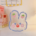 Clear square acrylic storage box with a cute cartoon rabbit design, sitting on a wooden desk.