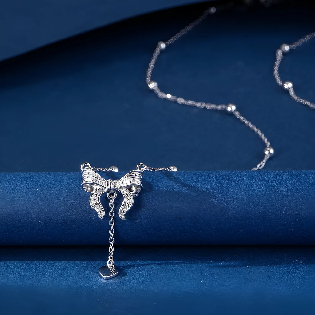 Silver necklace with heart-shaped pendant featuring bow detail on O-ring chain