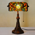Tiffany style table lamp with coloured stained glass shade on a resin base, shown on a desk.