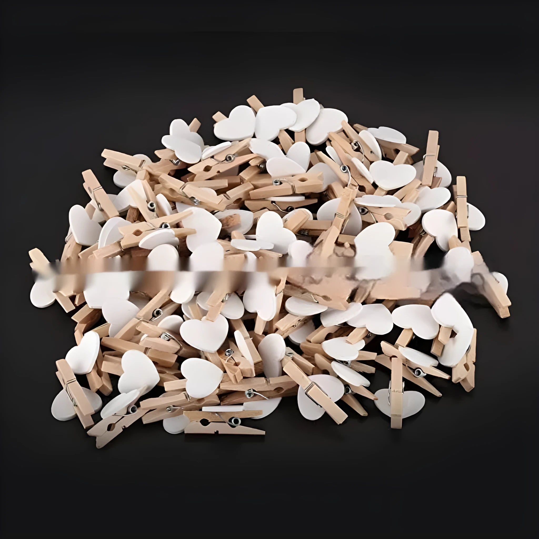 Five small wooden heart-shaped clips in red, pink, white, yellow, and rose colours on a wooden surface.