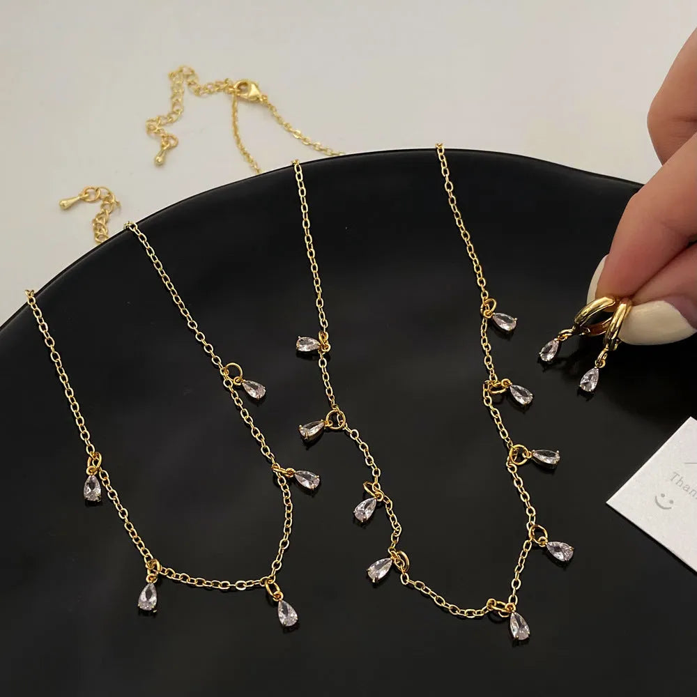 A zircon jewellery set comprising a geometric pendant necklace, stud earrings, and an anklet on a white background.