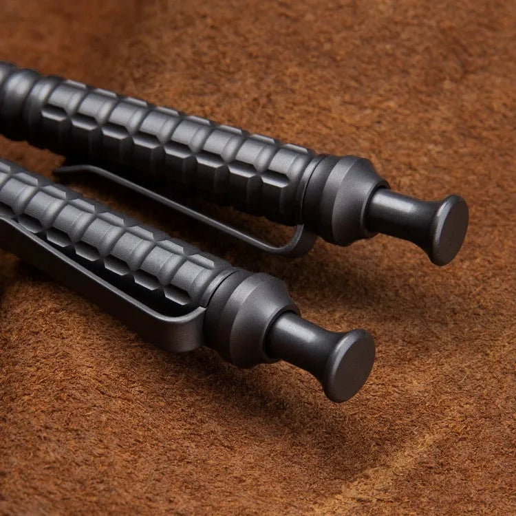 Gunmetal grey titanium alloy tactical pen with push-action mechanism on a gift box.