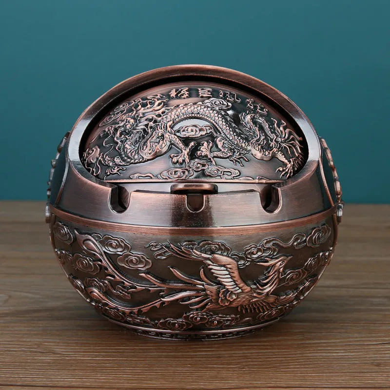 Alloy decorative ashtray in bronze with ornate peacock motif and cigarette extinguishing slot.
