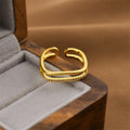 Geometric open ring in gold colour on a plain background.