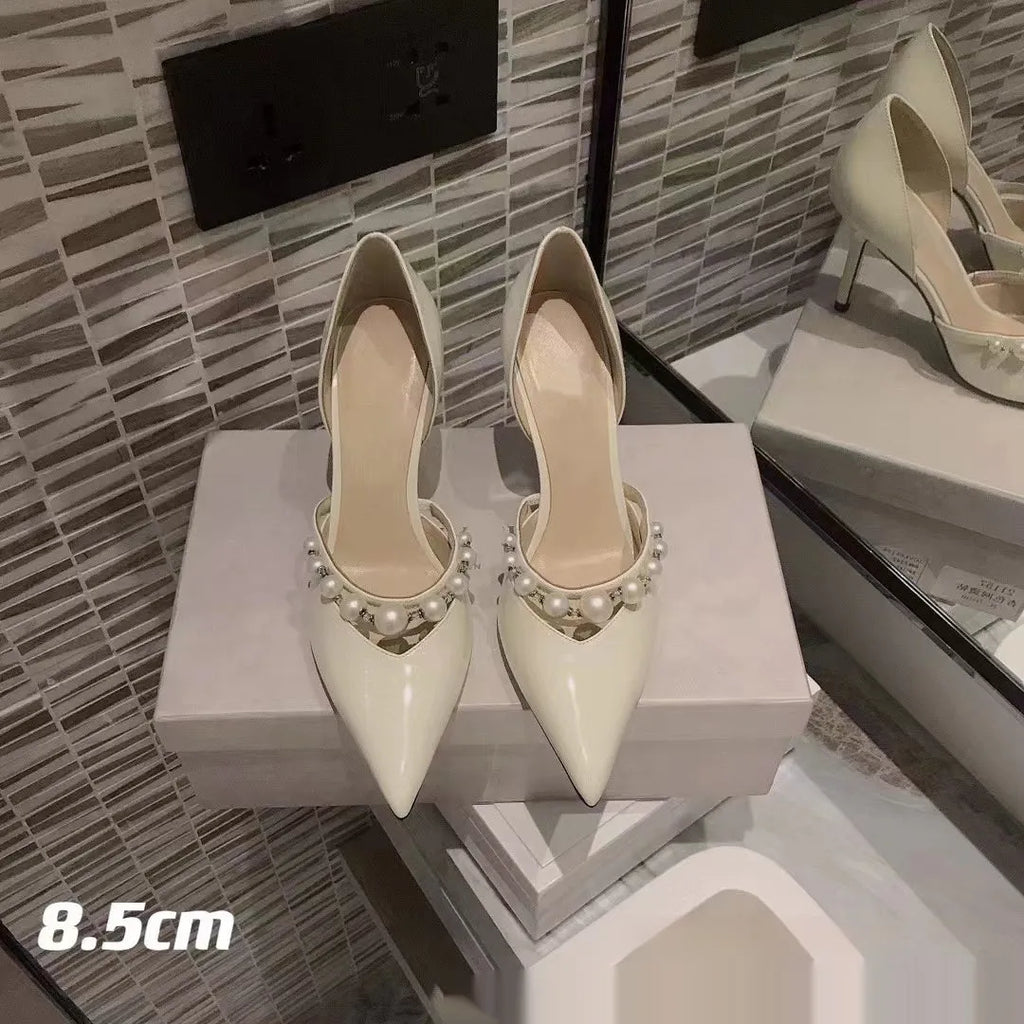 Women's nude pointed toe patent leather stiletto high heel with a pearl decoration on the side.