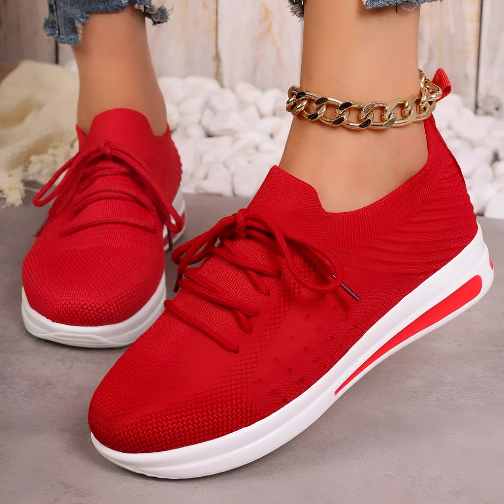 Women's low-top casual sneakers in red with front lace-up and round toe on a plain background.