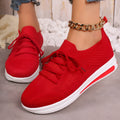 Women's low-top casual sneakers in red with front lace-up and round toe on a plain background.