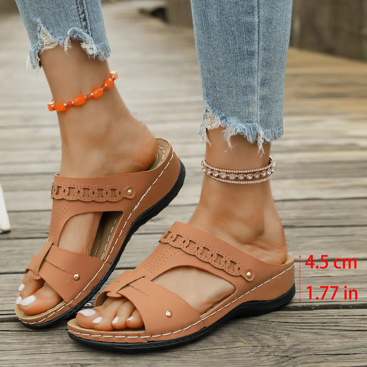 Pair of beige Roman style slippers with a fish mouth toe holder and slope heel on a rubber sole.