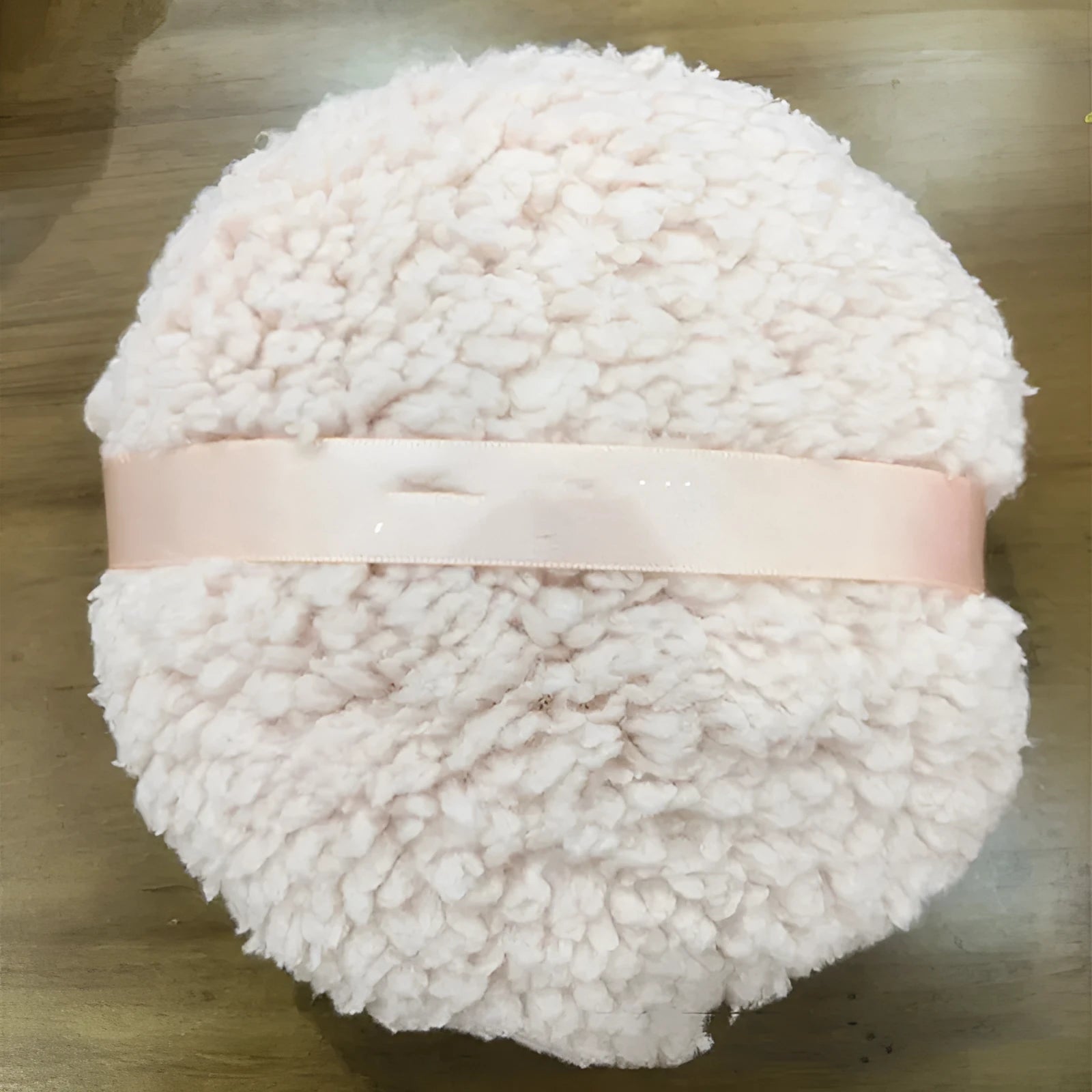 Large rectangular plush makeup powder puff in white on pink background.