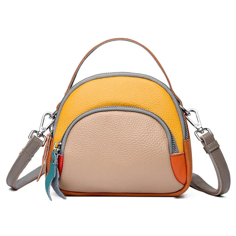 Round hand-held crossbody bag made from first layer cowhide leather with visible sewing line detail on exterior