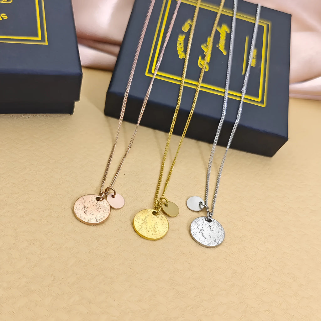 Round coin stainless steel pendant necklace in gold with adjustable side chain on a white background
