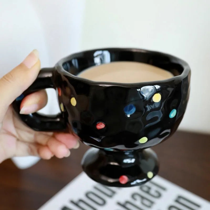 A hand-pinched ceramic mug with an irregular shape in a solid colour, shown on a table.
