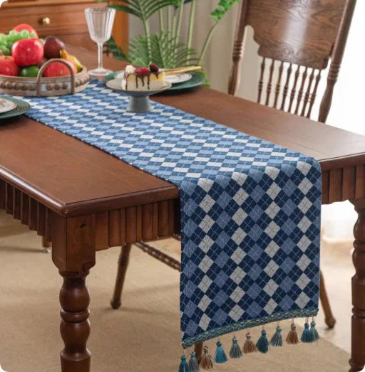 Country European retro style table flag with handwoven tassels in blue ginkgo leaf pattern lying on a wooden table.