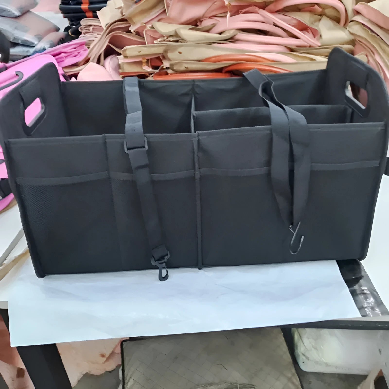 Foldable multi-compartment fabric car trunk storage box in black with a handle.
