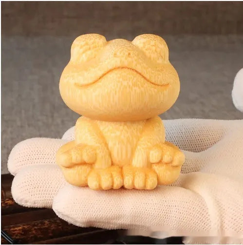 Solid bamboo carving of a smiling cartoon frog ornament, 5cm tall.