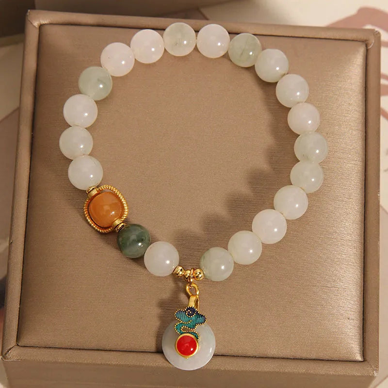 Women's ice jade bracelet with Xiangyun peace buckle and pearl details on a wrist.