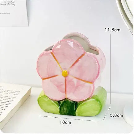 Ceramic pen holder box with floral decoration on a desk, holding pens.
