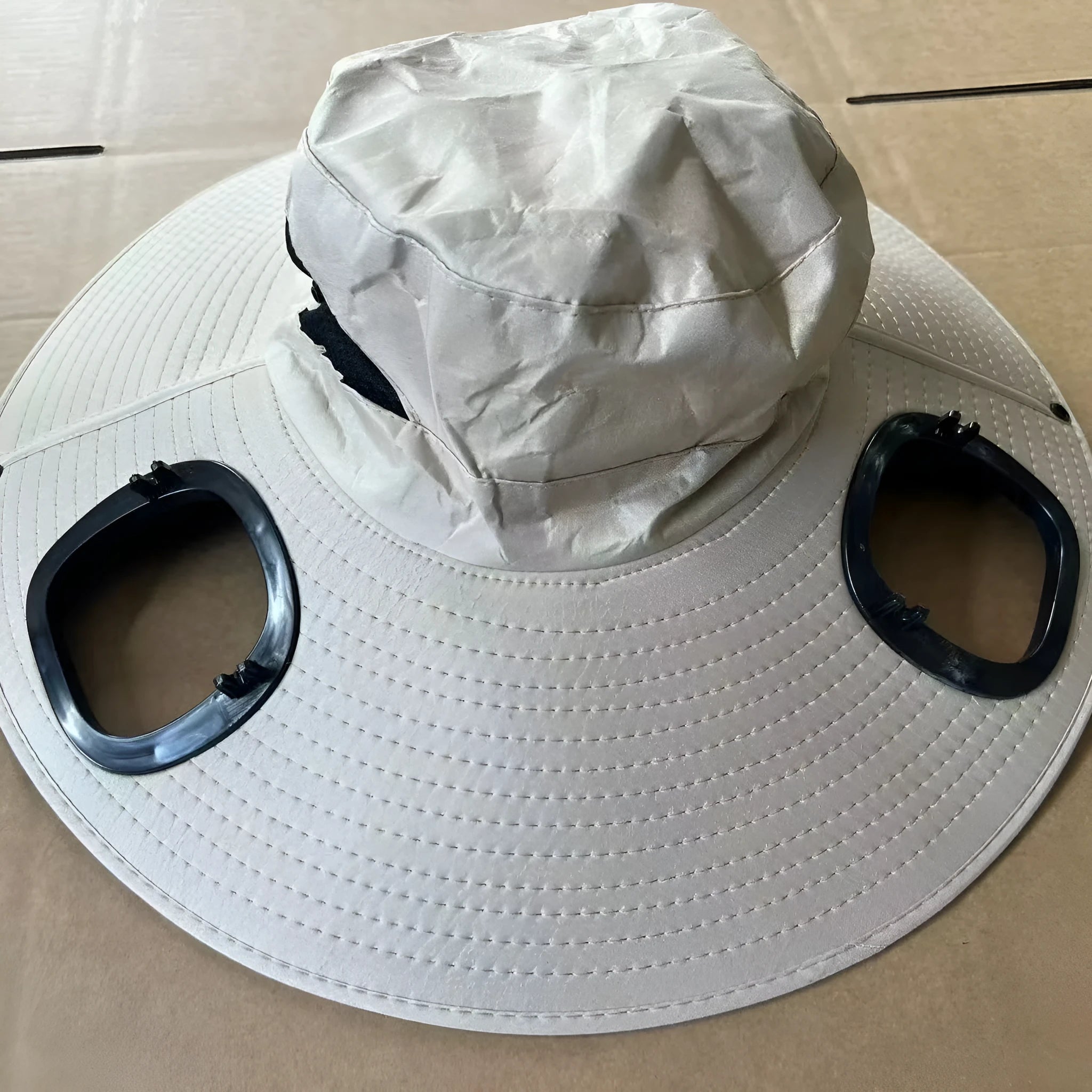 Man's grey solar fan cap with large brim and a small solar panel and fan visible on the front.