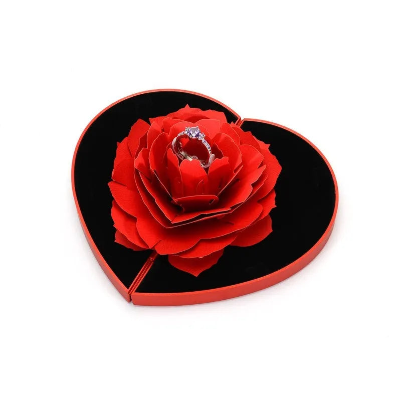 Red heart-shaped plastic ring box with a rose design and rotating 3D love text in the centre.